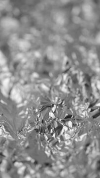 Metal silver aluminum foil with crumpled uneven surface texture, abstract vertical video