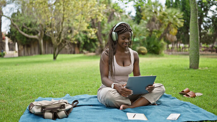 African american woman student using laptop and headphones at campus university