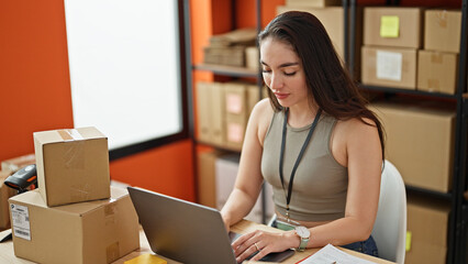 Young beautiful hispanic woman ecommerce business worker using laptop with serious face at office