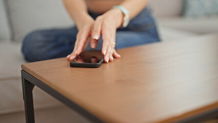 Young beautiful hispanic woman sitting on sofa holding smartphone at park