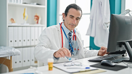 Middle age man doctor using computer at the clinic