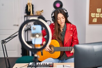 Young beautiful hispanic woman musician having online classical guitar concert at music studio