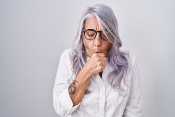 Middle age woman with tattoos wearing glasses standing over white background feeling unwell and...