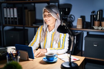 Fototapeta premium Middle age woman with grey hair working at the office at night with a happy and cool smile on face. lucky person.