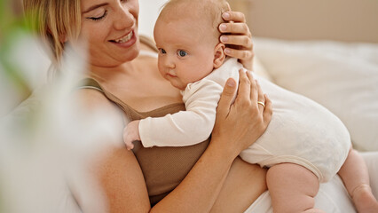 Mother and daughter lying on bed hugging at bedroom
