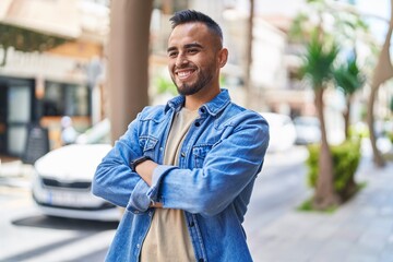 Young hispanic man smiling confident standing with arms crossed gesture at street