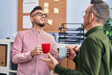 Two men business workers smiling confident drinking coffee at office