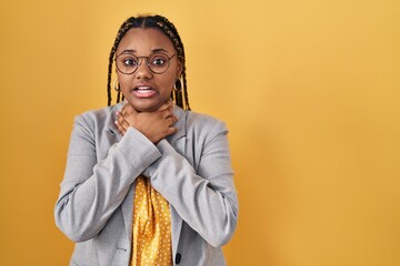 African american woman with braids standing over yellow background shouting and suffocate because painful strangle. health problem. asphyxiate and suicide concept.