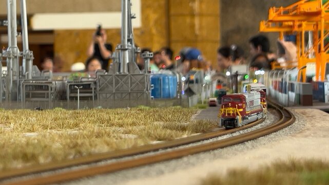 LOS ANGELES, SEP 10, 2023: detail of model train heading towards camera with soft focus on people in background. Model railway exhibit at Union Station in Downtown.
