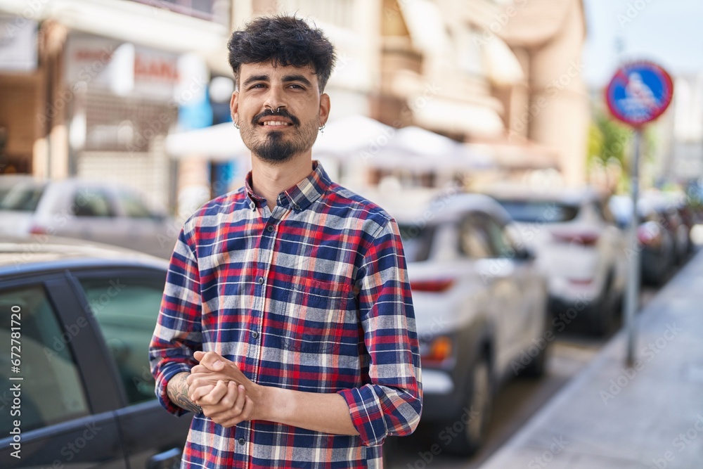 Sticker Young hispanic man smiling confident standing at street