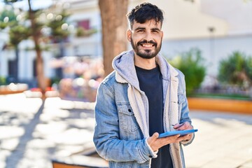 Young hispanic man smiling confident using touchpad at park