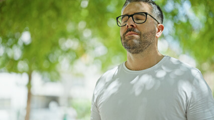 Grey-haired man breathing with closed eyes at park