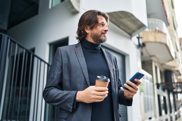Obraz na płótnie Canvas Middle age man using smartphone drinking coffee at street