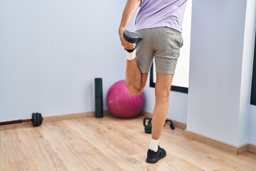 Middle age man stretching leg on back view at sport center