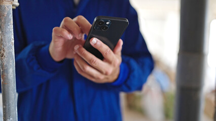 Young hispanic man worker using smartphone at construction site