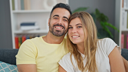 Fototapeta premium Man and woman couple hugging each other sitting on sofa at home
