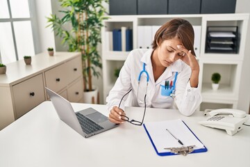 Young beautiful hispanic woman doctor stressed working at clinic