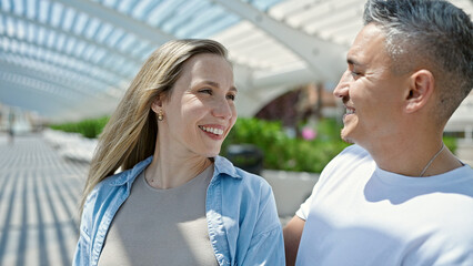 Naklejka premium Man and woman couple looking each other standing together at park