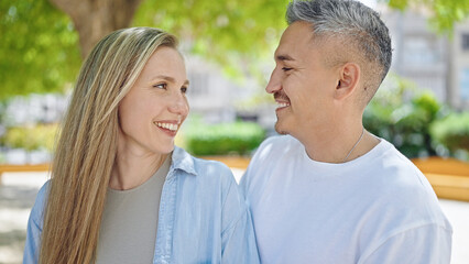 Fototapeta premium Man and woman couple looking each other standing together at park