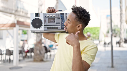 African american man holding boombox doing thumb up gesture at street