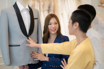 Beautiful female designer presenting wedding dress at shop. woman shop owner for pre wedding at wedding interior fashion studio.
