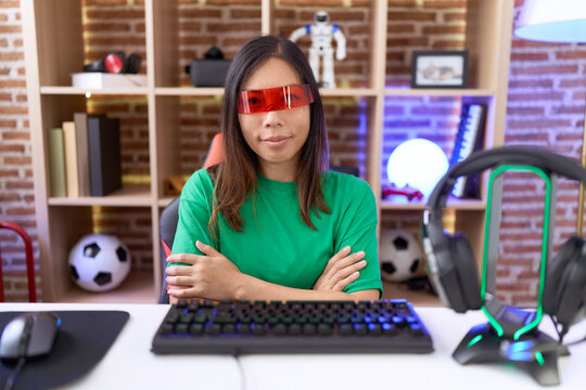 Middle age chinese woman wearing virtual reality glasses happy face smiling with crossed arms looking at the camera. positive person.