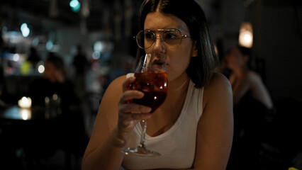 Young beautiful hispanic woman drinking a glass of red wine at the restaurant