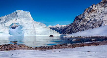 Adventure tourists near an iceberg grounded in a shallow inlet of Franz Joseph Fjord in eastern Greenland.