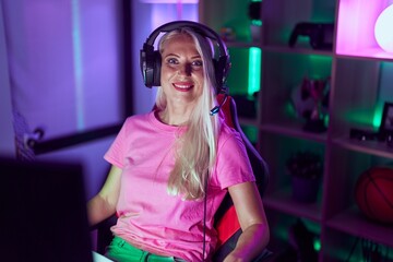 Young blonde woman streamer smiling confident using computer at gaming room