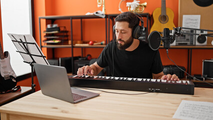 Young hispanic man musician having online piano lesson at music studio