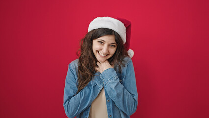 Young beautiful hispanic woman smiling confident wearing christmas hat over isolated red background