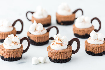 Homemade mini cheesecakes shaped like cups of hot cocoa with marshmallows.