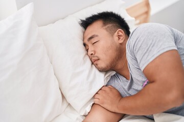 Young chinese man lying on bed sleeping at bedroom