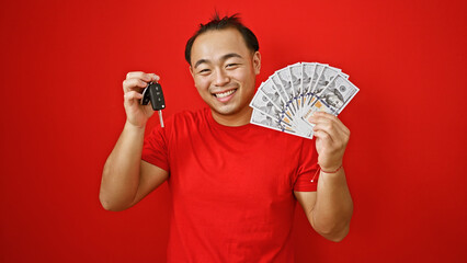 Joyous young chinese male holding the key to his new ride over a red isolated background, smiling...