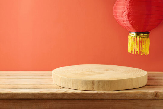 Empty wooden log podium on table and traditional lanterns over red background. Chinese New Year mock up for design and product display.