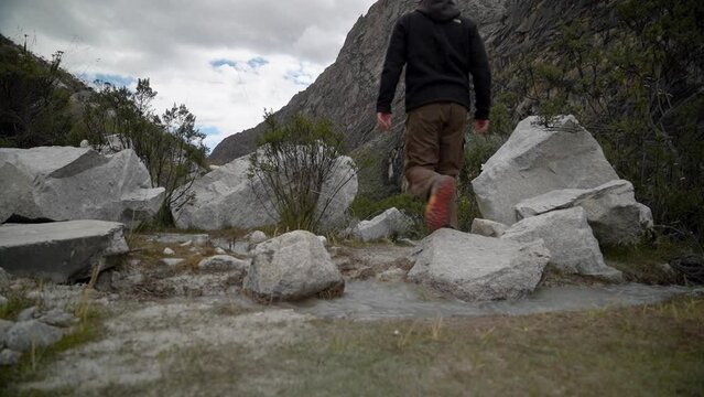 young caucasian man hiking through the mountainous landscape of the cordillera blanca in the Andes mountains of Peru near laguna Paron.