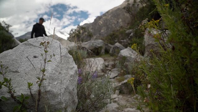 young caucasian man hiking through the mountainous landscape of the cordillera blanca in the Andes mountains of Peru near laguna Paron.