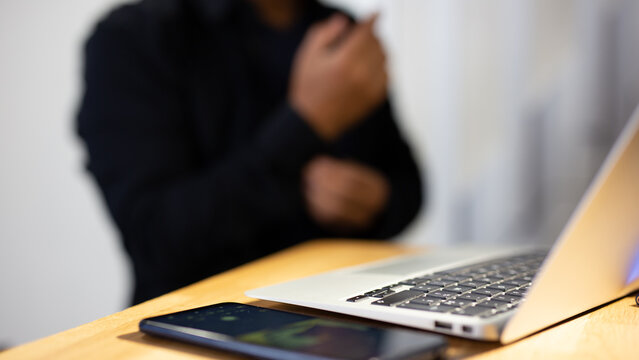 Hands operating a laptop with a vigilant eye on a hacker's silhouette in the background, illustrating the battle against cyberattacks. Hacker Defense