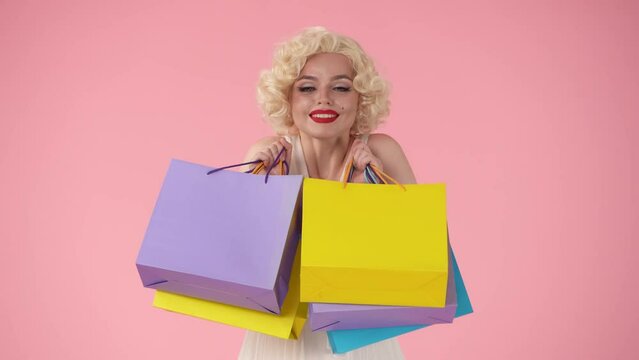 Young happy woman holding colorful shopping bags. Woman looking like in studio on pink background. Shopping concept, sales, black Friday.