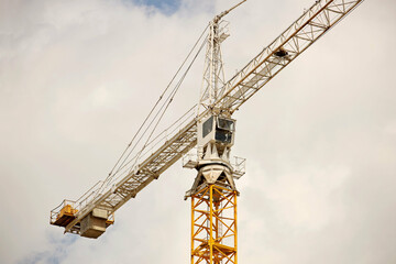 Tower cranes work during the construction of a multi-story building. New apartments for residents and premises for offices. Risky work at height. Lifting heavy building materials. City development