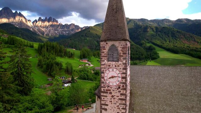 Italy Dolomites Aerial 4K Video Rising Drone Reveal Shot of Santa Maddalena Church Tower and Majestic Odle Peaks Rocks Scenic Alpine Village Landscape in Val di Funes South Tyrol Travel
