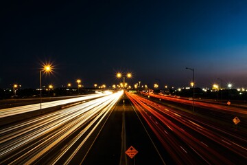 Long exposure shot of night traffic on a freeway near street lights
