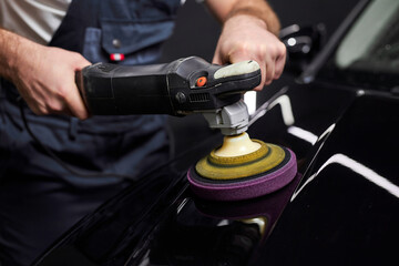 male auto repair man doing car polish with machine, professional auto detailer hand holding rotary...