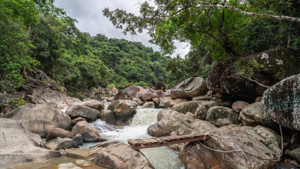 Jungle waterfall with rapid waters and large rocks in Vietnam.