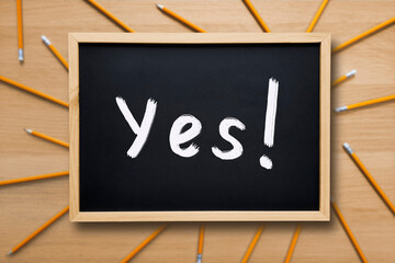 Yes Word on a school board. Yes concept. Text written with white chalk on a blackboard on...