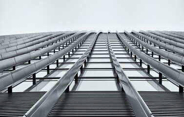 Low angle of a modern building against a cloudy sky in grayscale