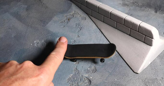 A man rides a fingerboard, practicing skills to perform an impossible trick