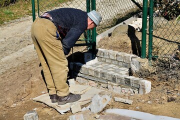 Bricklayer assembles and bricks the stairway around the house from concrete blocks