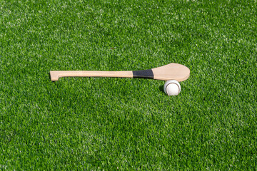 Hurling bat and sloitar on green grass. Horizontal sport theme poster, greeting cards, headers, website and app - obrazy, fototapety, plakaty