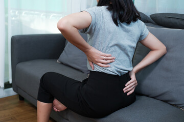 Asian woman aching back spinal pain from stress of injury, painful ache stress muscle cramp, body upper muscle problem, indeed of medical physical therapy concept, home living room coach lifestyle - Powered by Adobe